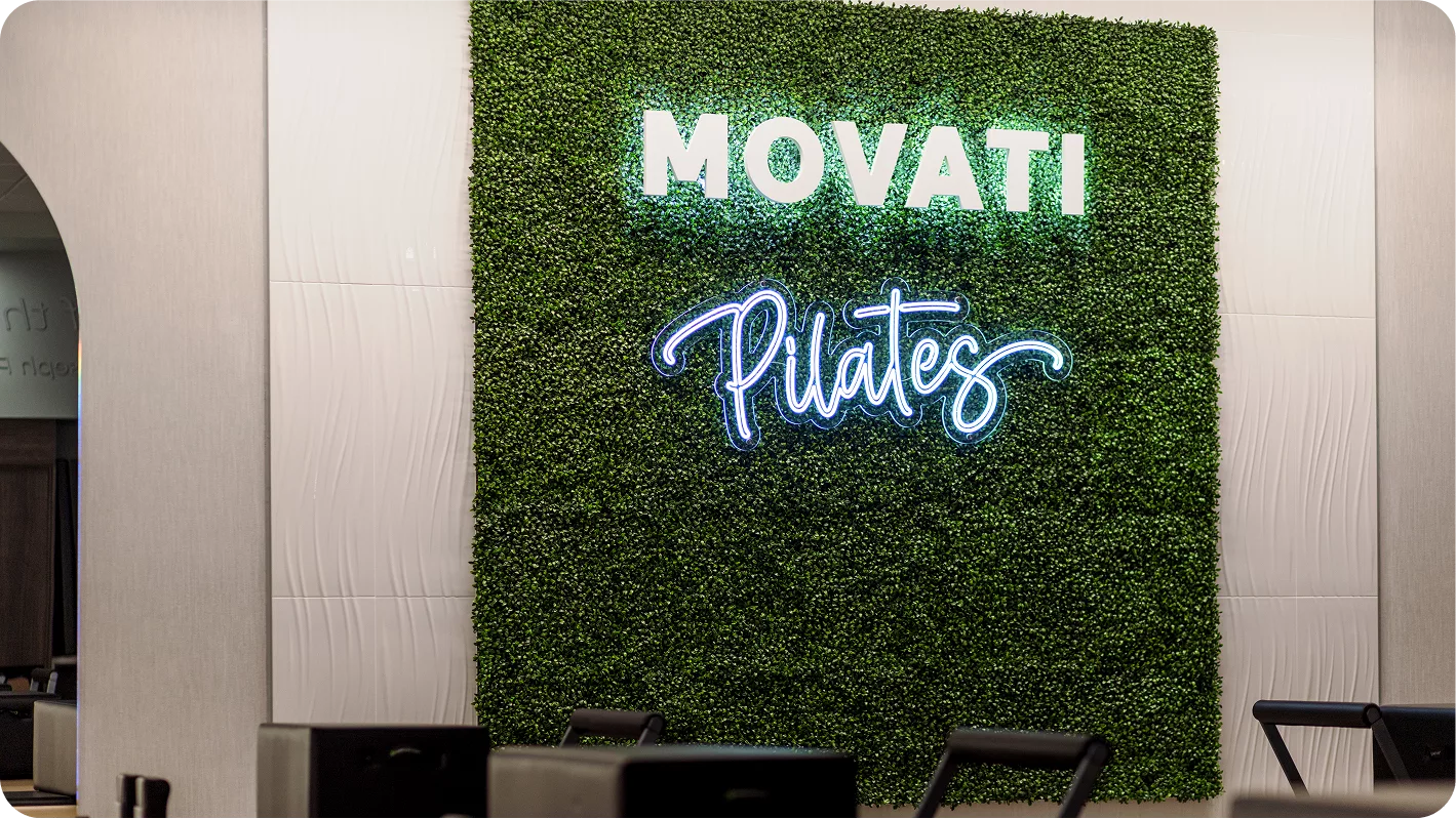 Wall Pilates workouts in a modern gym with Pilates reformer machines under soft lighting.